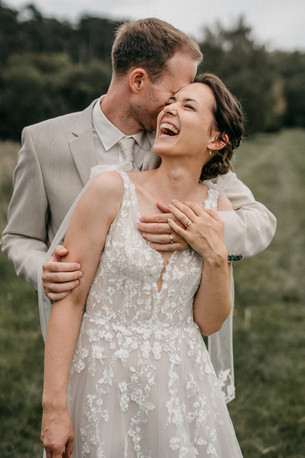 a groom and a laughing bride. Cuddeling during their wedding.