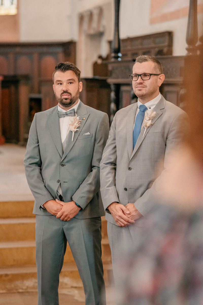 two men in suits standing in a church