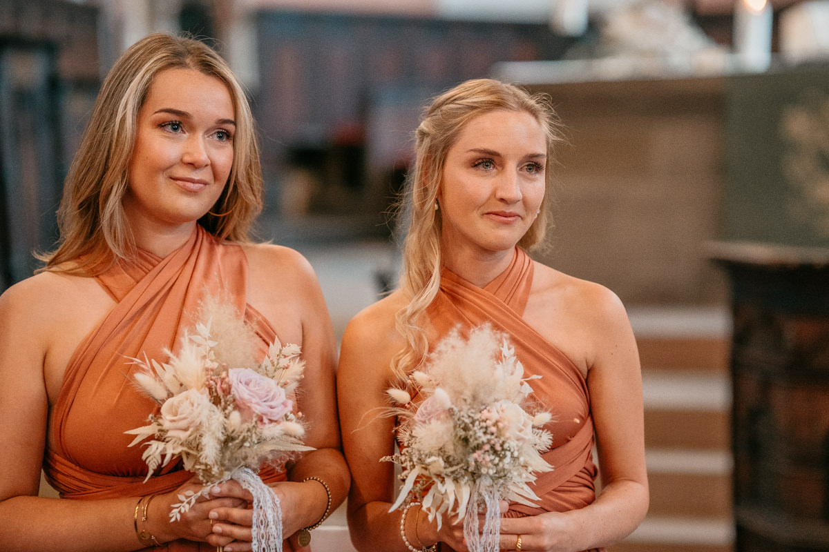 two women in orange dresses holding flowers