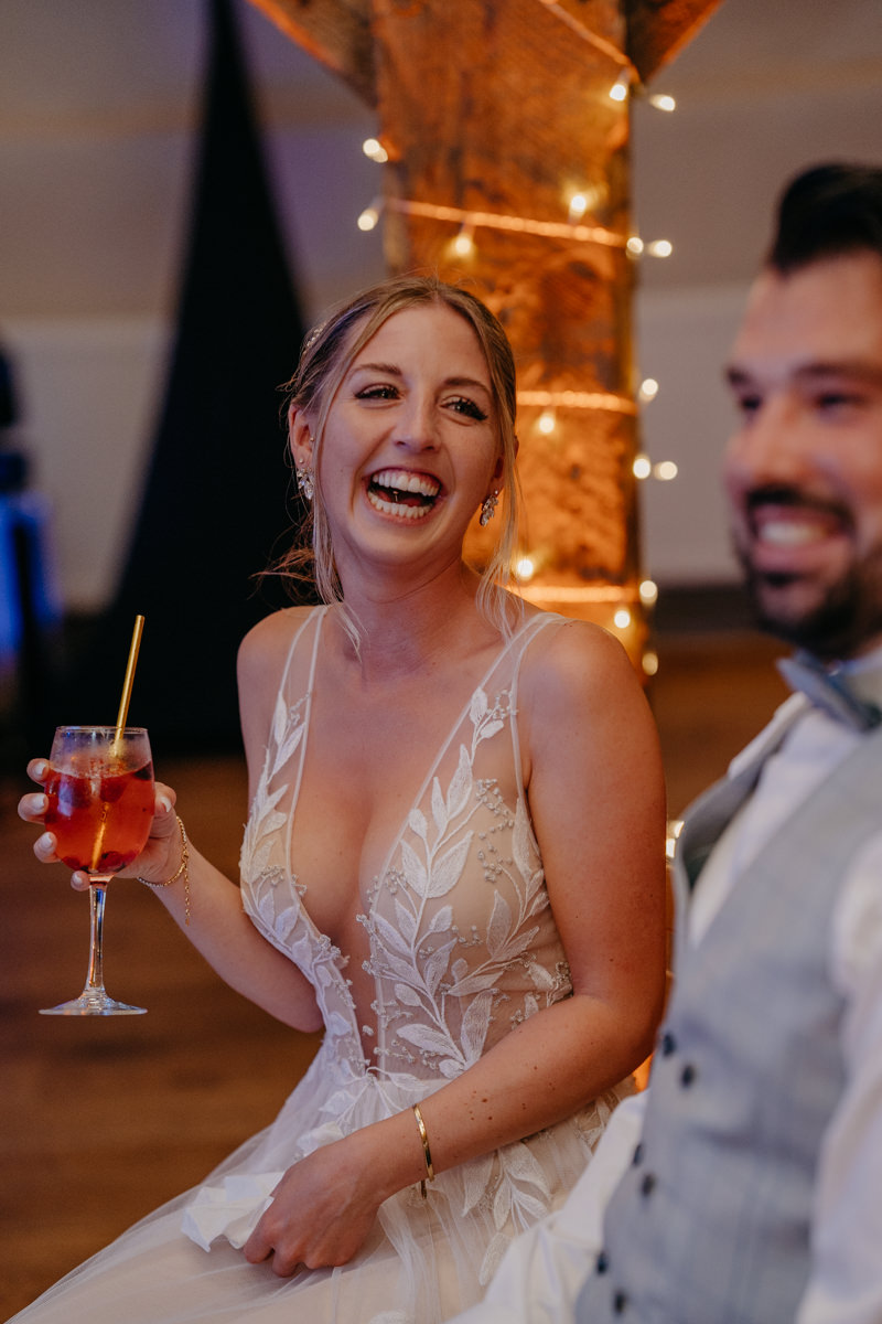 a bride laughing and holding a drink