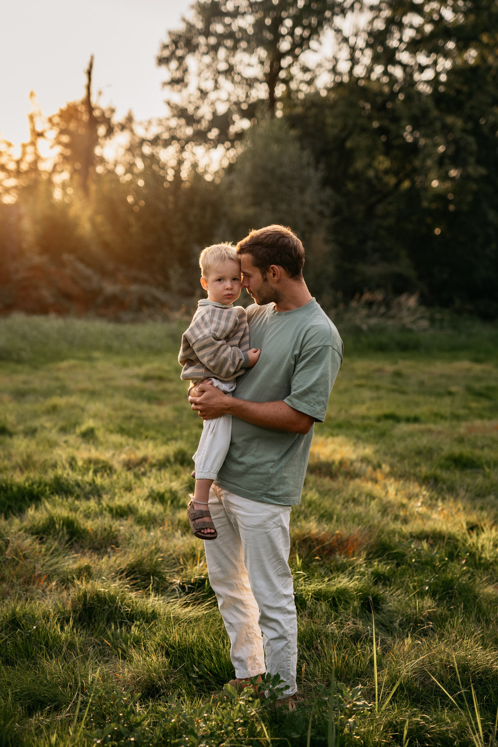 a man holding a baby in a grassy field