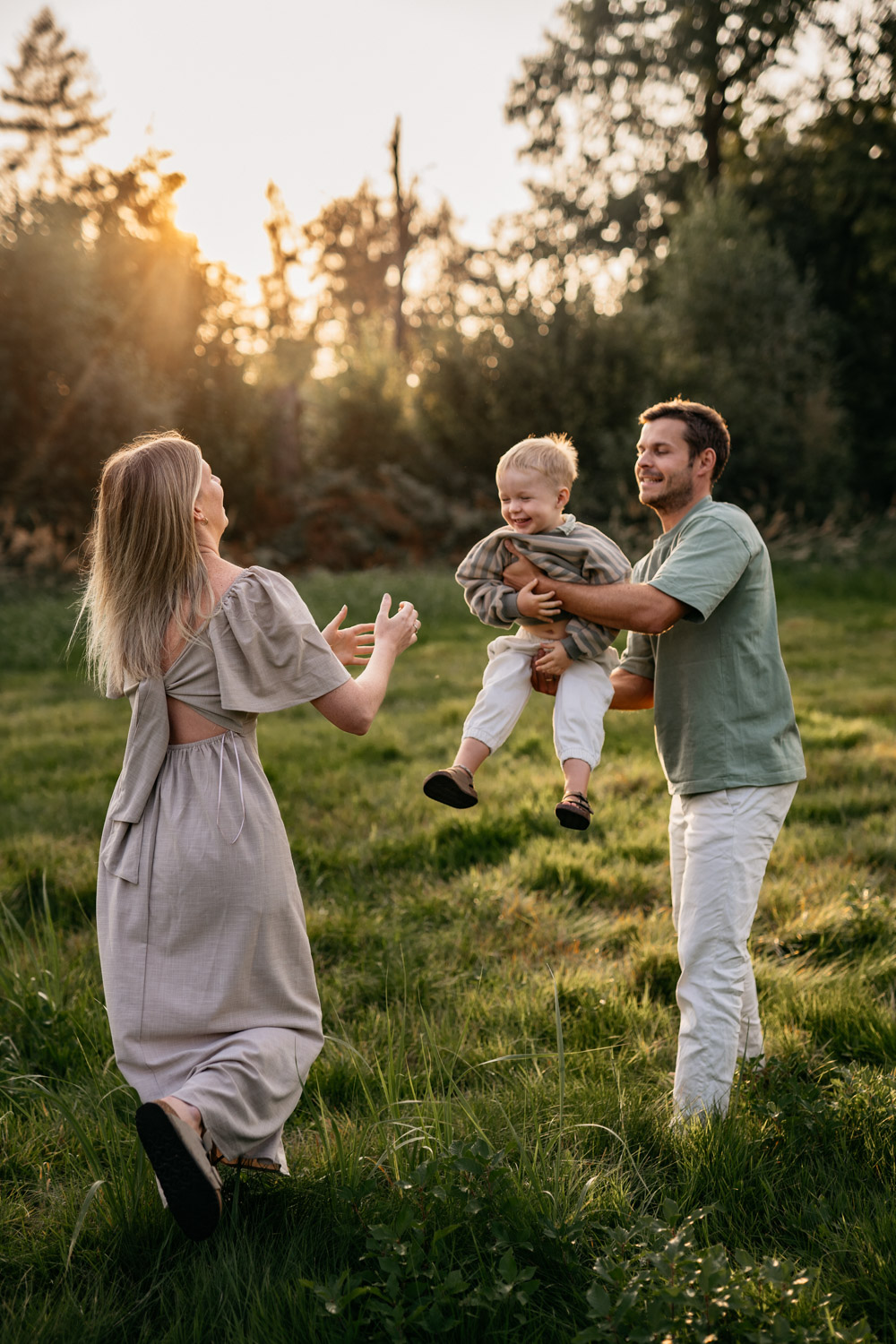 a man and woman holding a baby in a grassy field