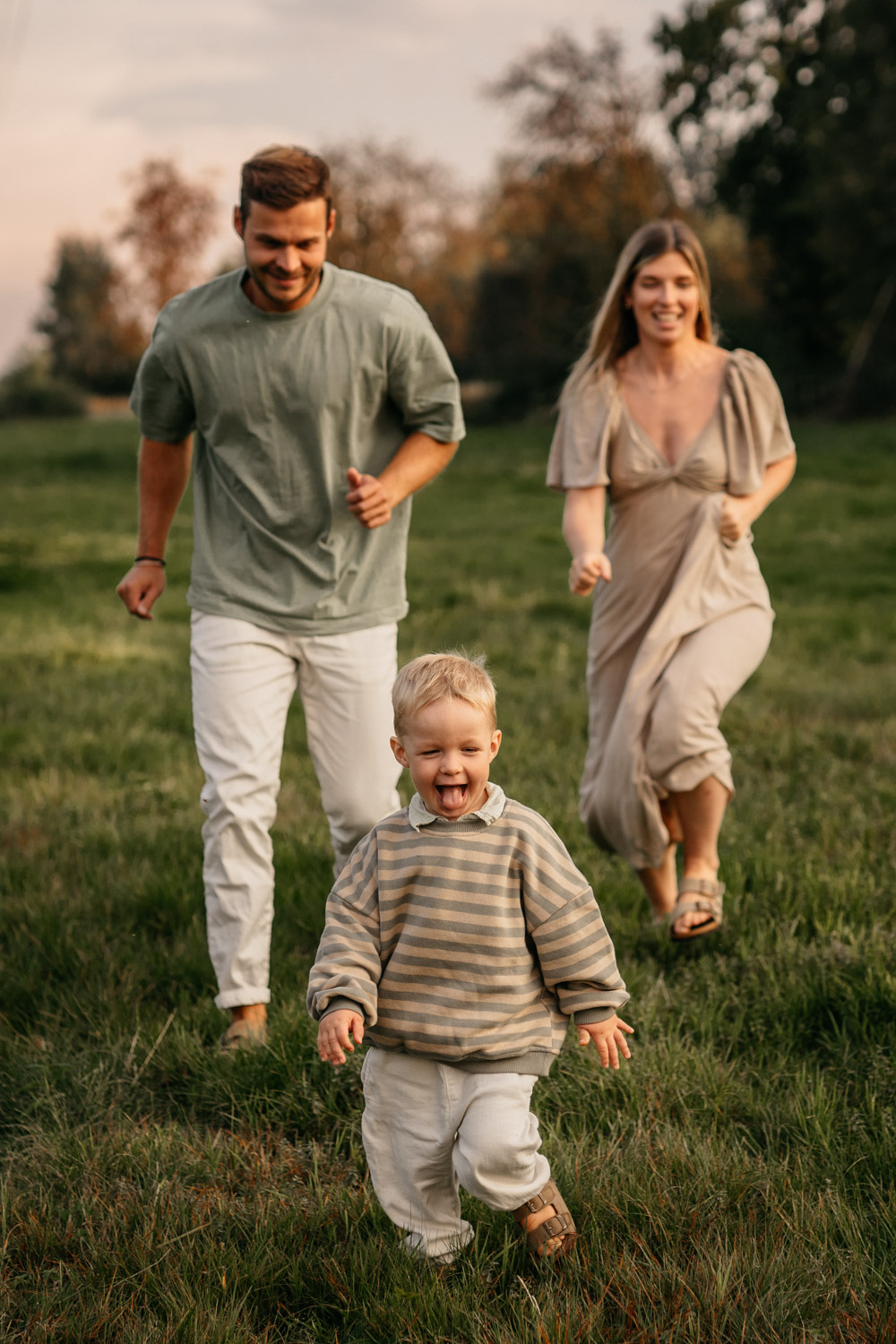 a man and woman running in a grassy field with a child