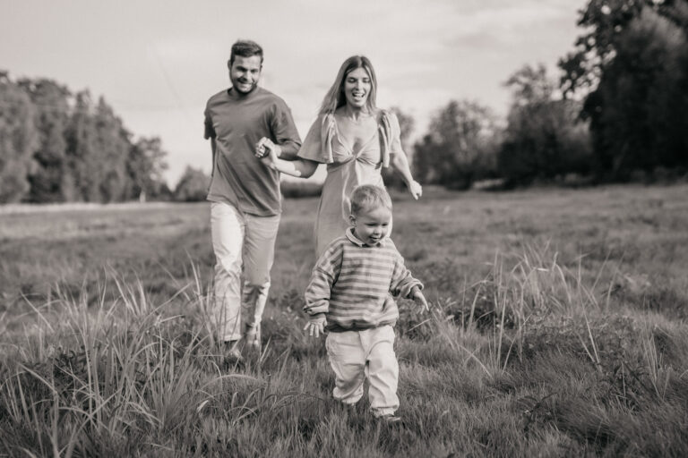 a man and woman holding hands and running after her child in a field