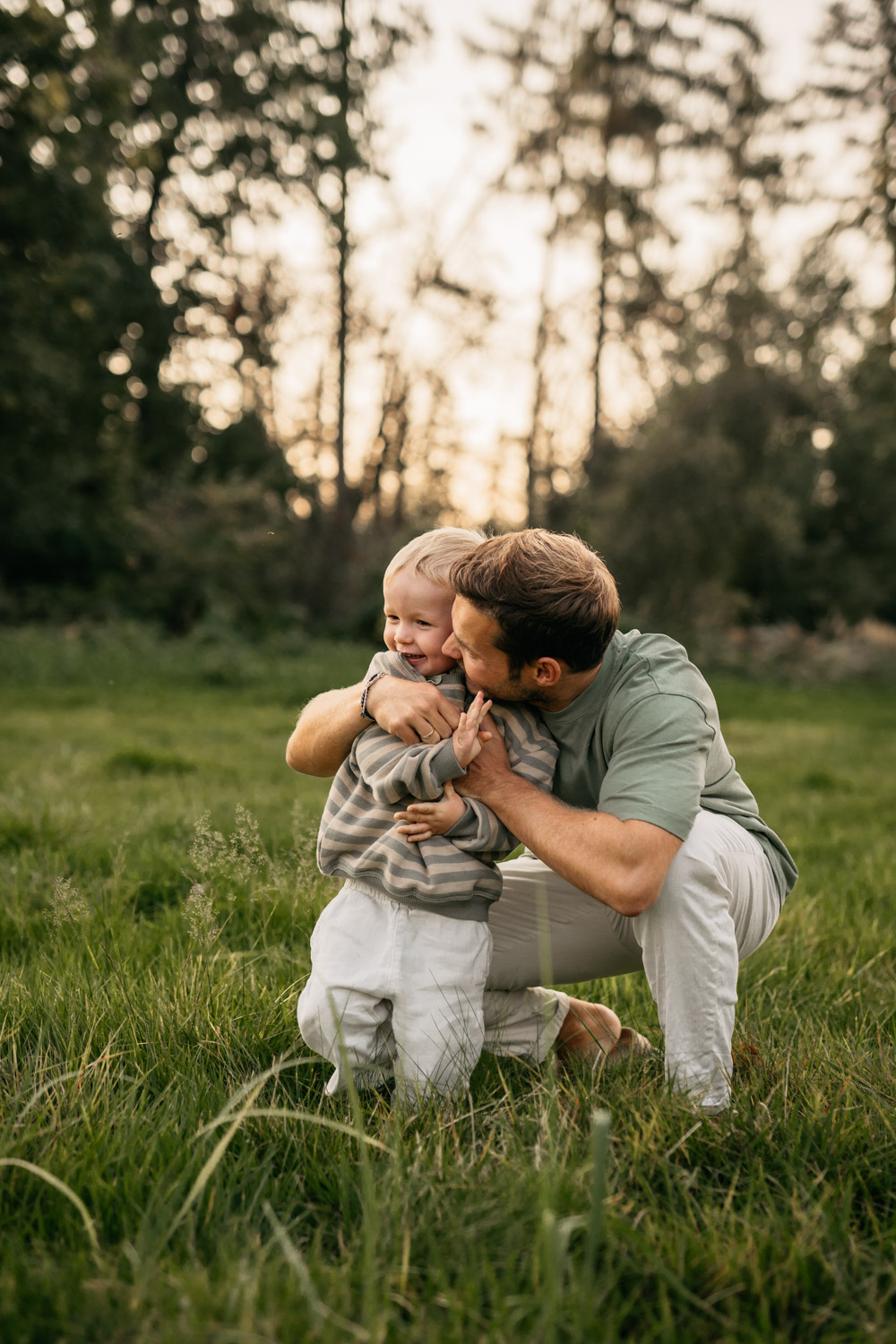 a man kissing a child on the cheek in a grassy field