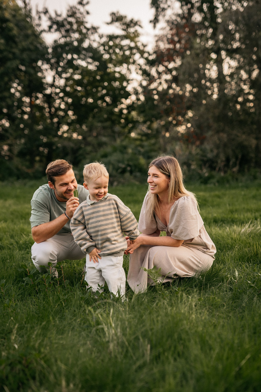 a man and woman with a child in a grassy field