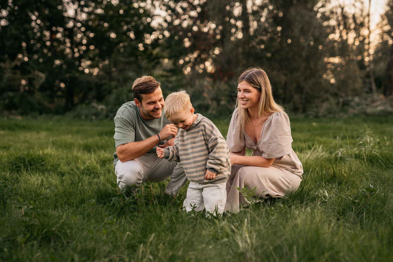 a man and woman with a child in a grassy field