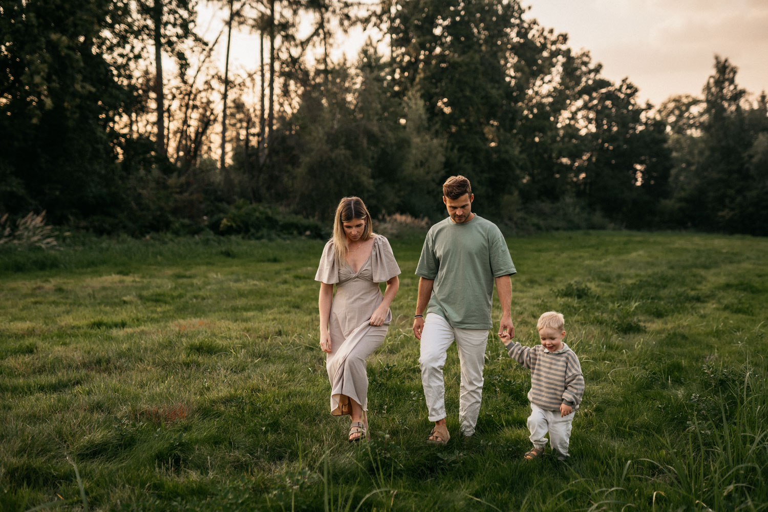 a man and woman walking with a child in a grassy field