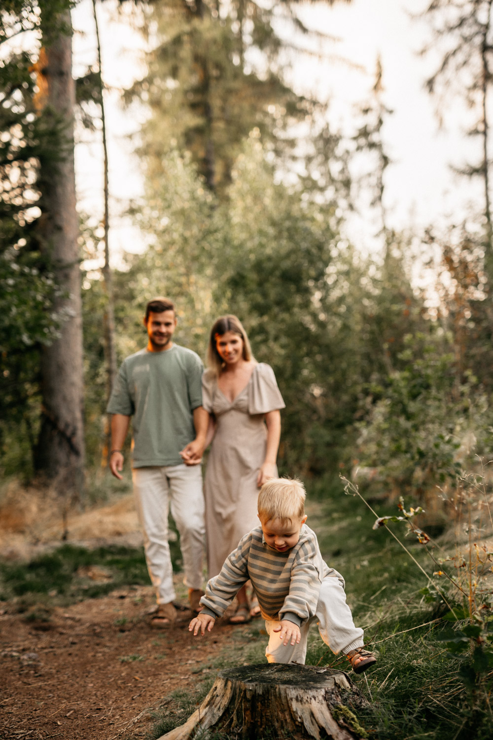 a man and woman holding hands and a child walking in the woods