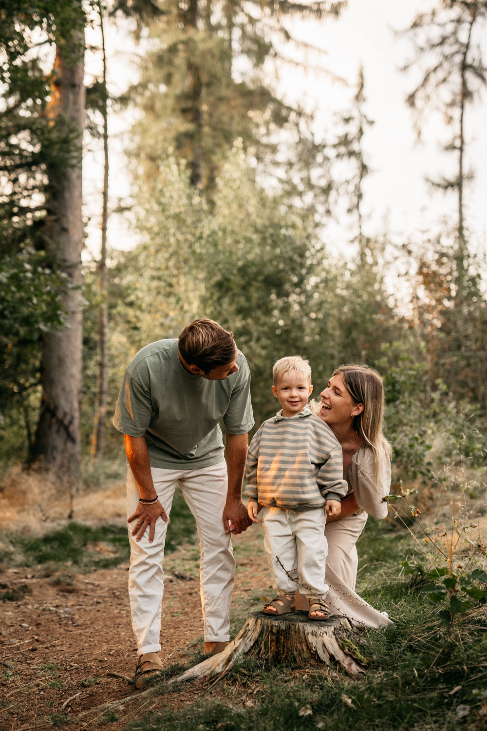 a man and woman standing next to a child in a forest