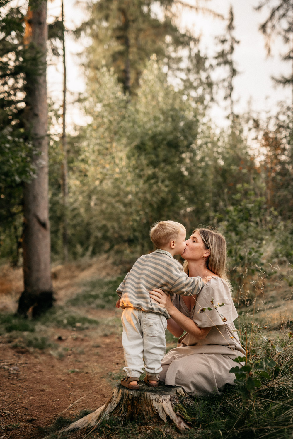 a mother kissing a child in a forest