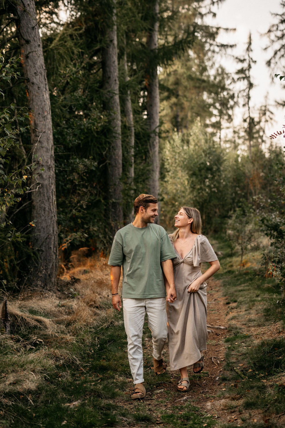 a man and woman holding hands in a forest