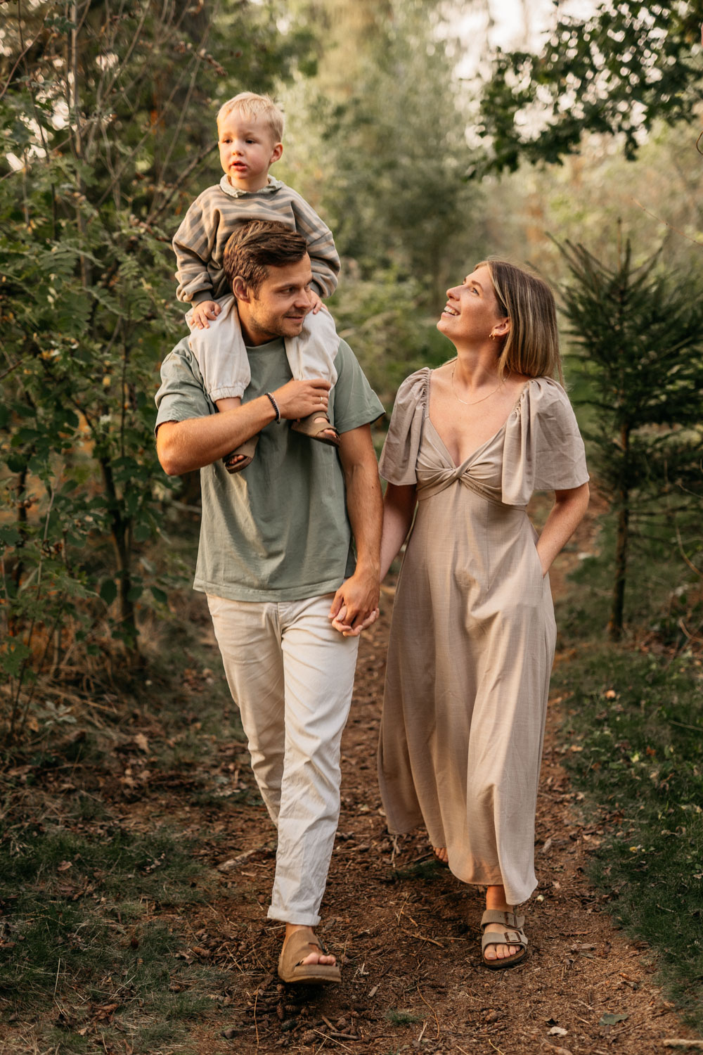 a man and woman holding hands and a child on his shoulders