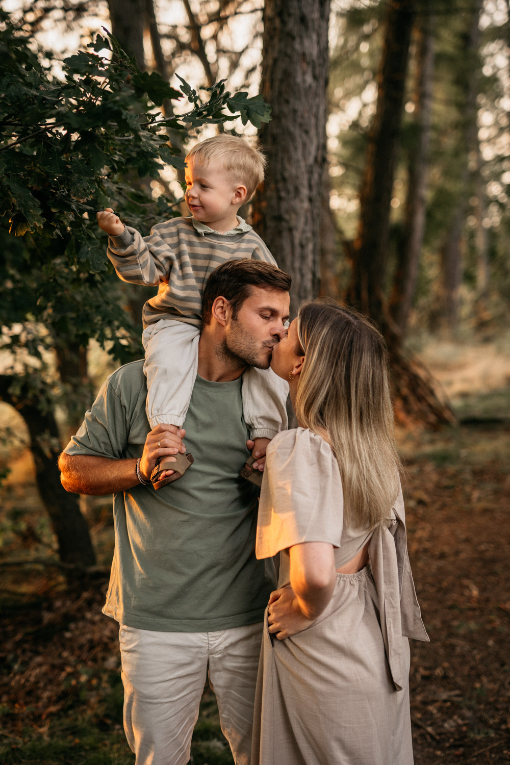 a man and woman kissing a child on their shoulders