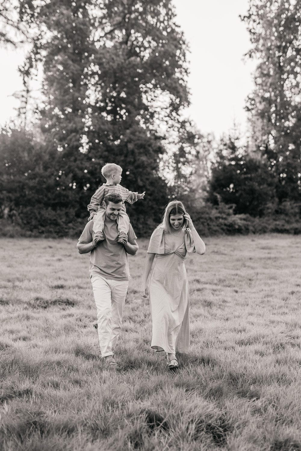 a man and woman walking in a field with a child on his shoulders