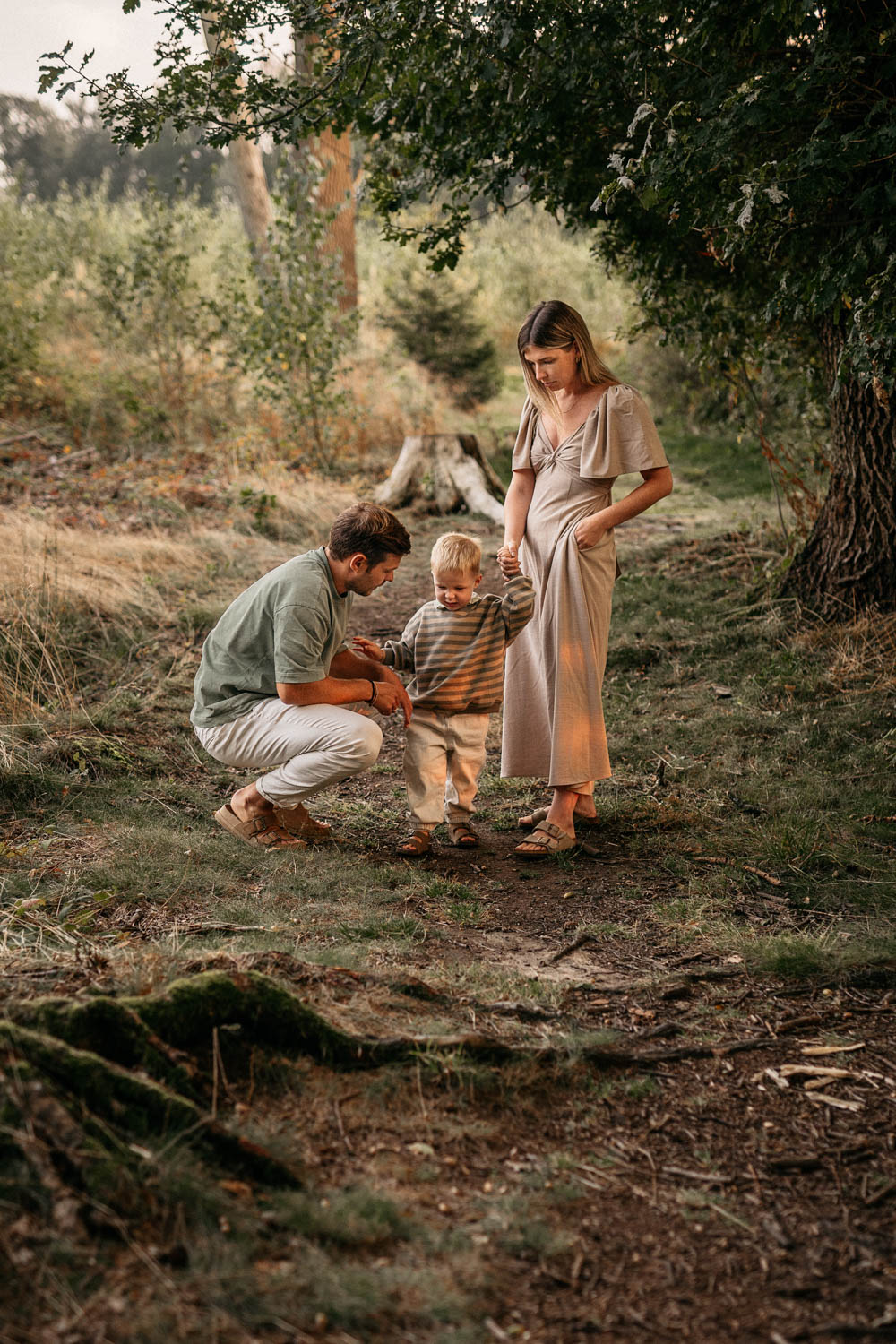 a father and mother standing in a forest with a child