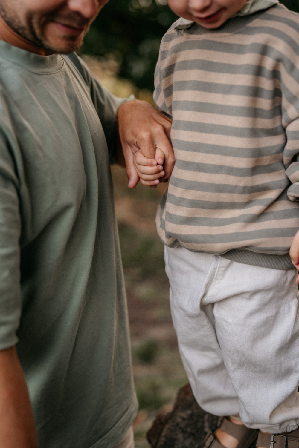 a man holding a hand of his two year old child