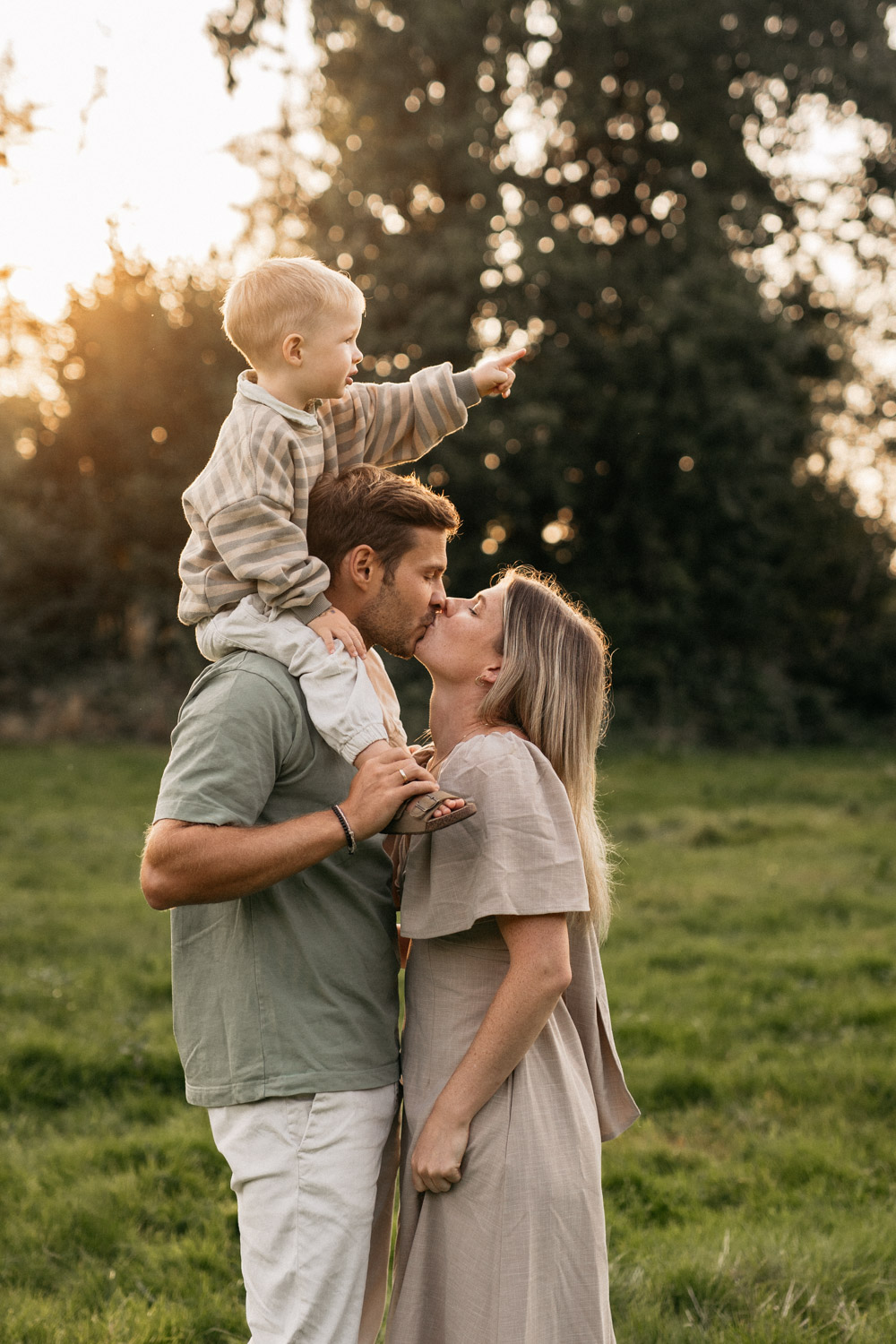 a man and woman kissing a child on their shoulders