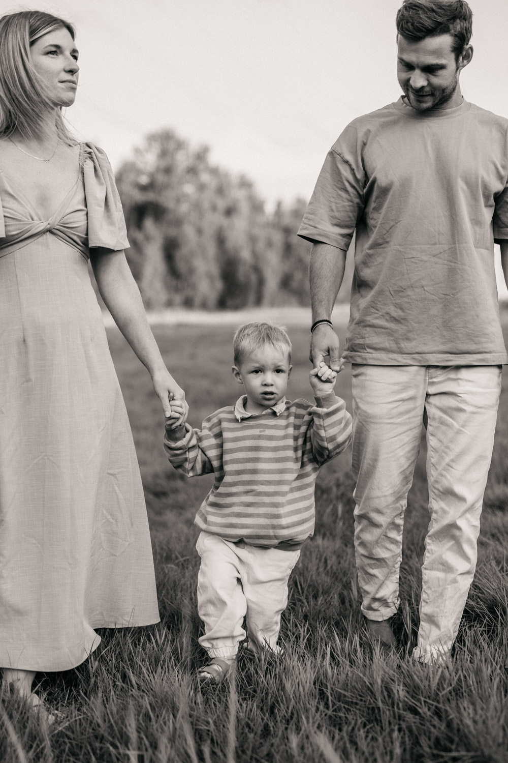 a man and woman holding hands and walking with a child