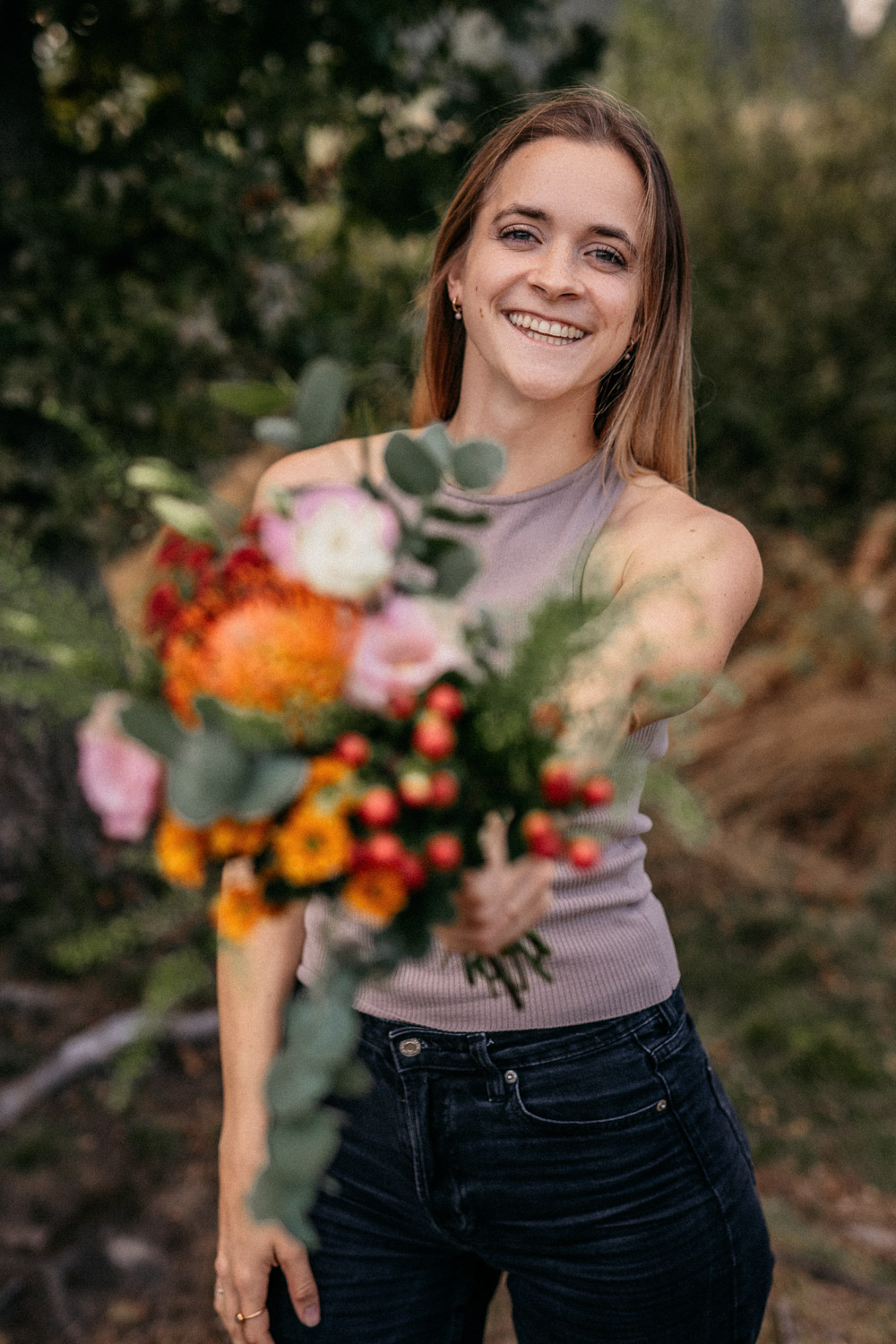 Porträt einer Hochzeitsfotografin die einen Brautstrauß in die Kamera hält und lacht